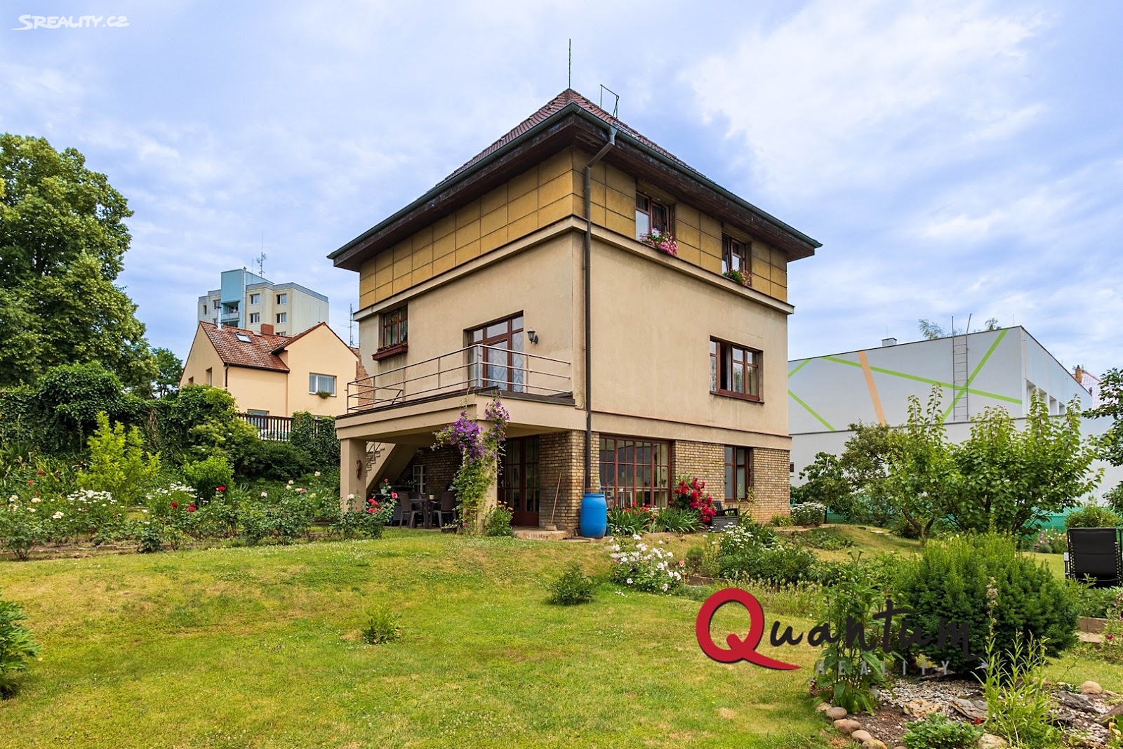 Jihozápadní průčelí vily od zahrady: cihelné přízemí, balkon v patře, okrové 3. NP a stanová střecha. Stav před rekonstrukcí, 2023.